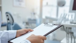 Dental professional holding a clipboard in a modern dental operatory