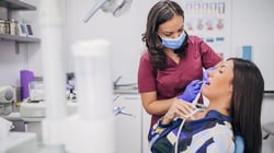 Dentist using dental equipment to examine a patient in a modern dental clinic operatory.