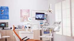 Modern dental operatory with chair, overhead equipment, and clinical workstations in a bright, organized office environment.