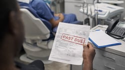 Dental Employee holding a past due payment notice in their hand in a dental office