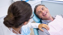 Dentist with her hand on patients shoulder. Patient is smiling and happy, demonstrating trust and communication.