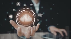 Illustrated cloud upload icon floating above an open hand, surrounded by digital technology symbols representing cloud-based software features.