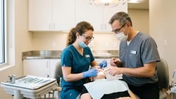 Dental hygienist and dentist collaborating during a patient exam in a modern well-lit operatory
