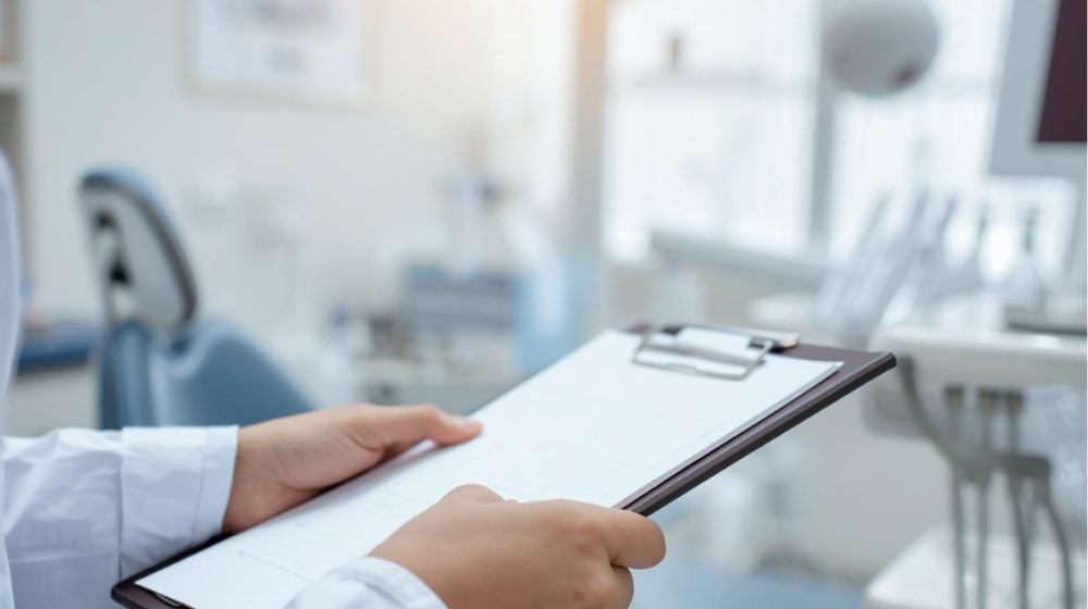 Dental professional holding a clipboard in a modern dental operatory