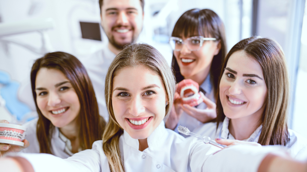 Smiling dental team standing together in a clinic, illustrating a supportive workplace and strong staff retention