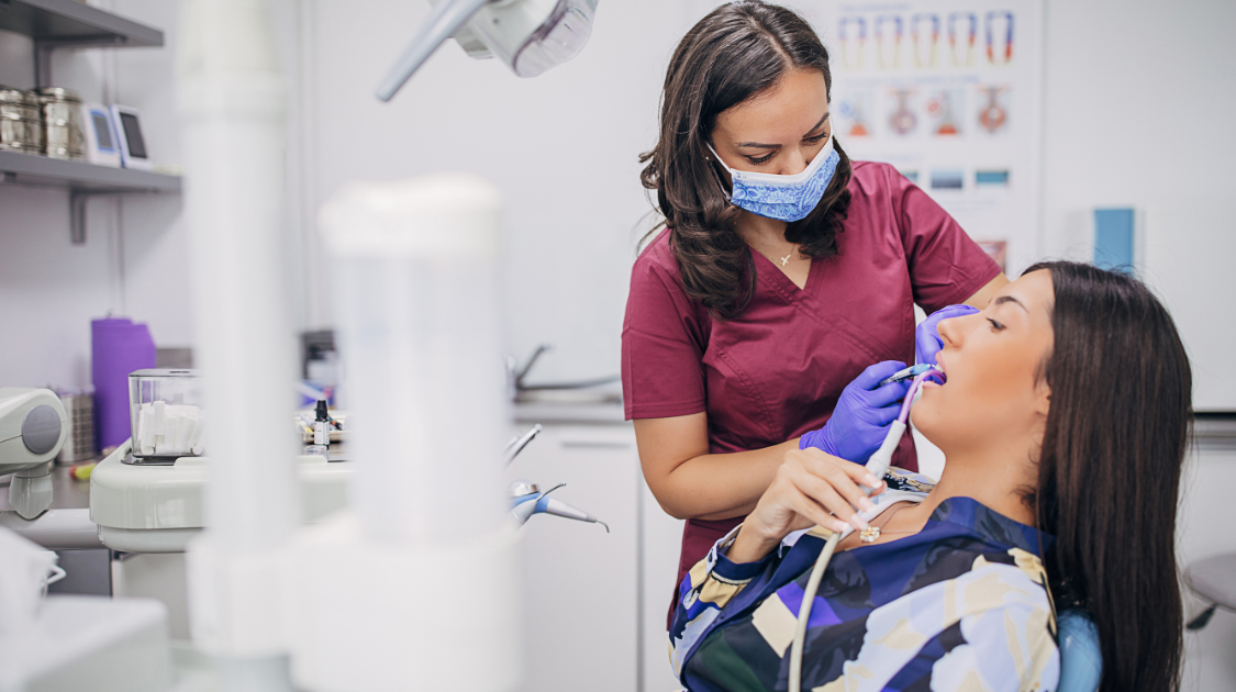 Dentist using dental equipment to examine a patient in a modern dental clinic operatory.