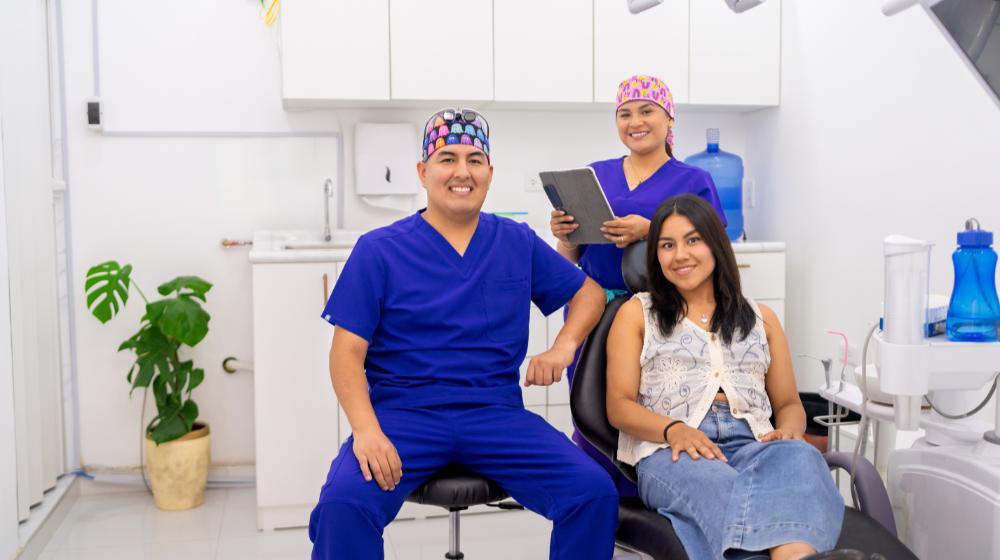 Friendly dental team standing with a patient seated in a dental chair