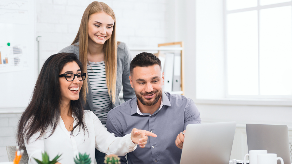 Three Dental Office Employees Looking and Pointing at Computer to Asses Dental Software Options. 