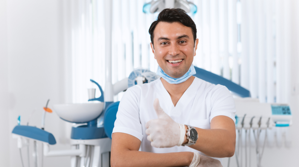 Male Dentist holding thumbs up in dental office