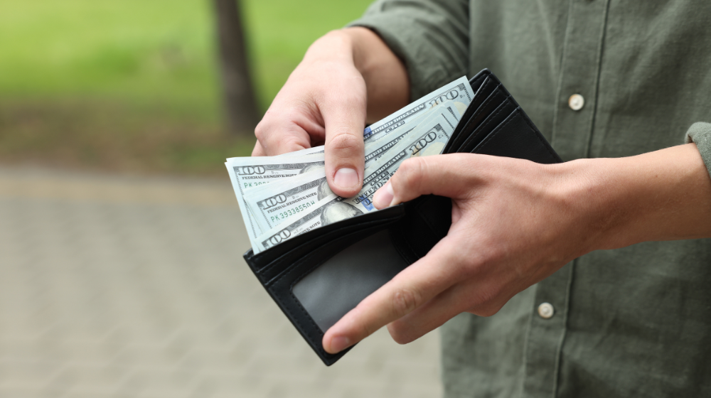 Illustration of dollar bills being placed into a wallet, symbolizing faster cash flow and next-day funding for dental practices.