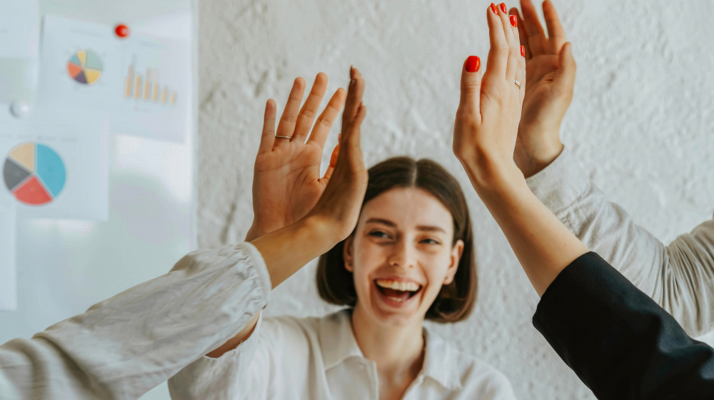 Team members celebrate together with a high-five, reflecting confidence, support, and a positive work environment.