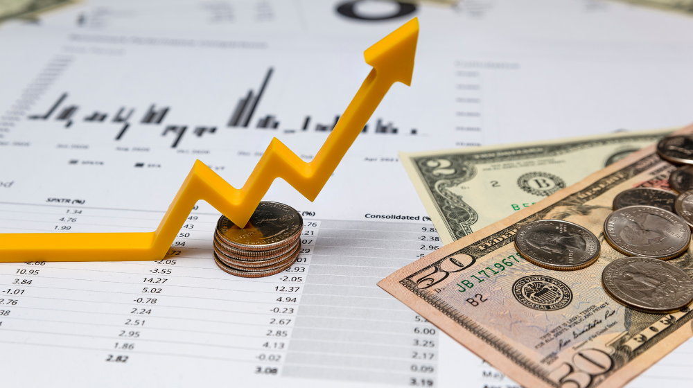 Coins, dollar bills, and an upward arrow on financial charts, representing growth in dental practice revenue