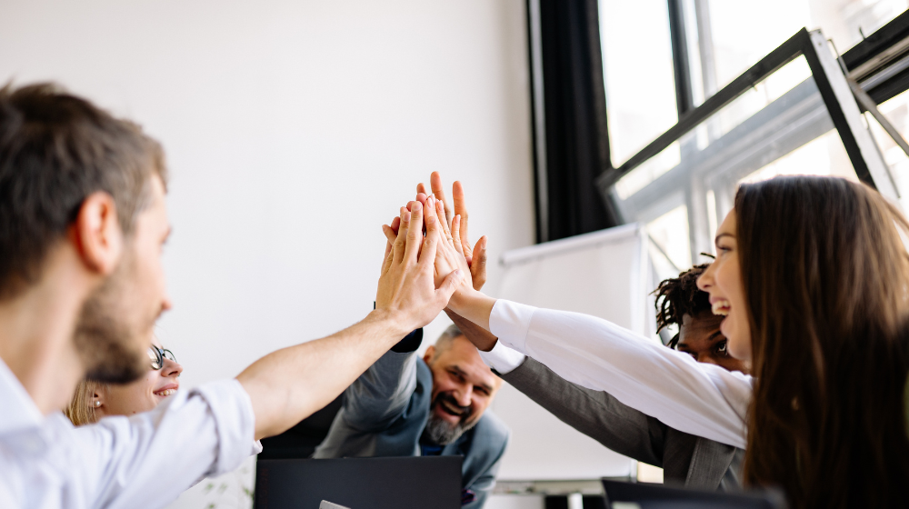 Dental Team with hands in middle, high-fiving during daily dental huddle
